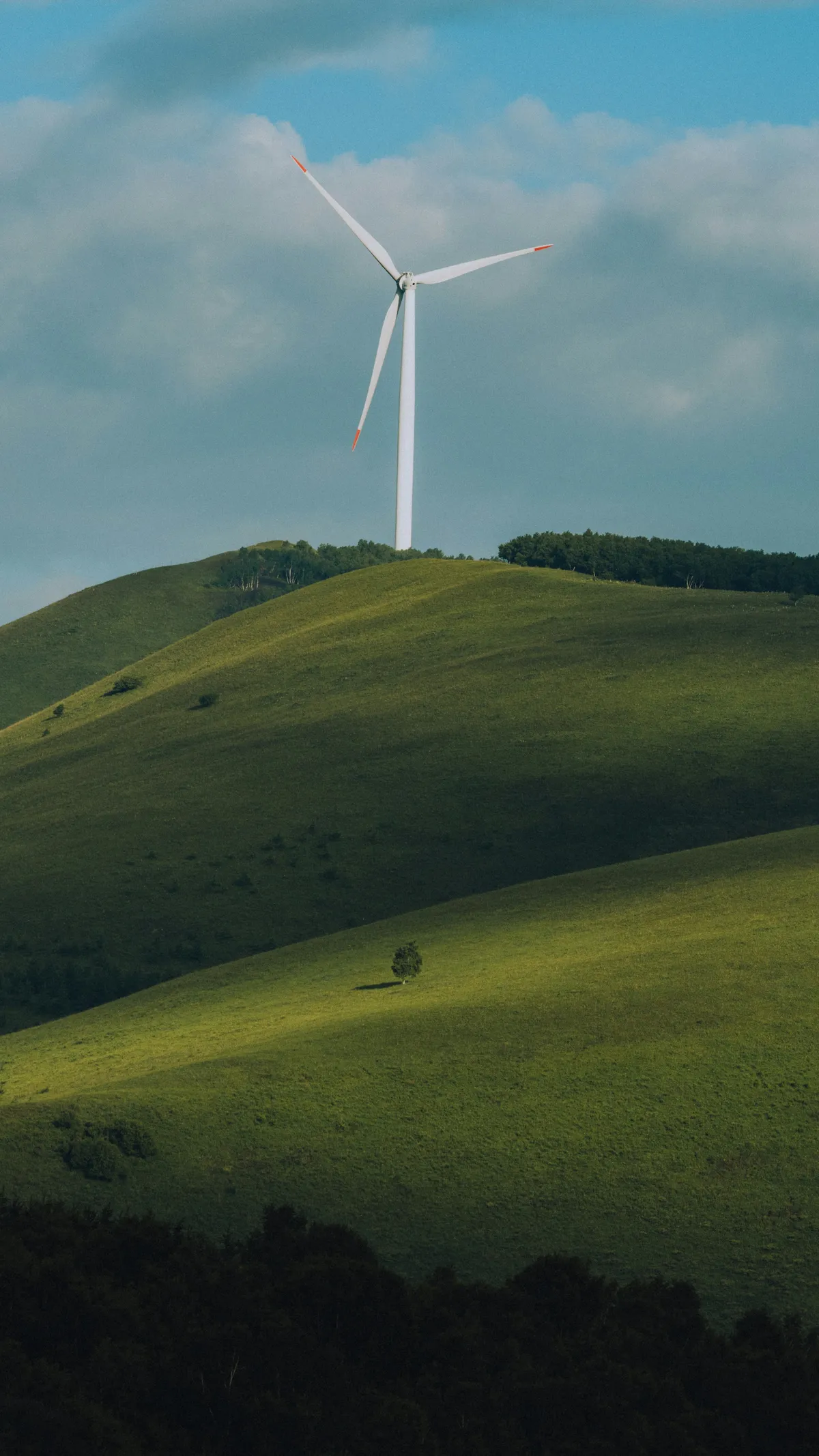 Turbină eoliană pe dealuri verzi